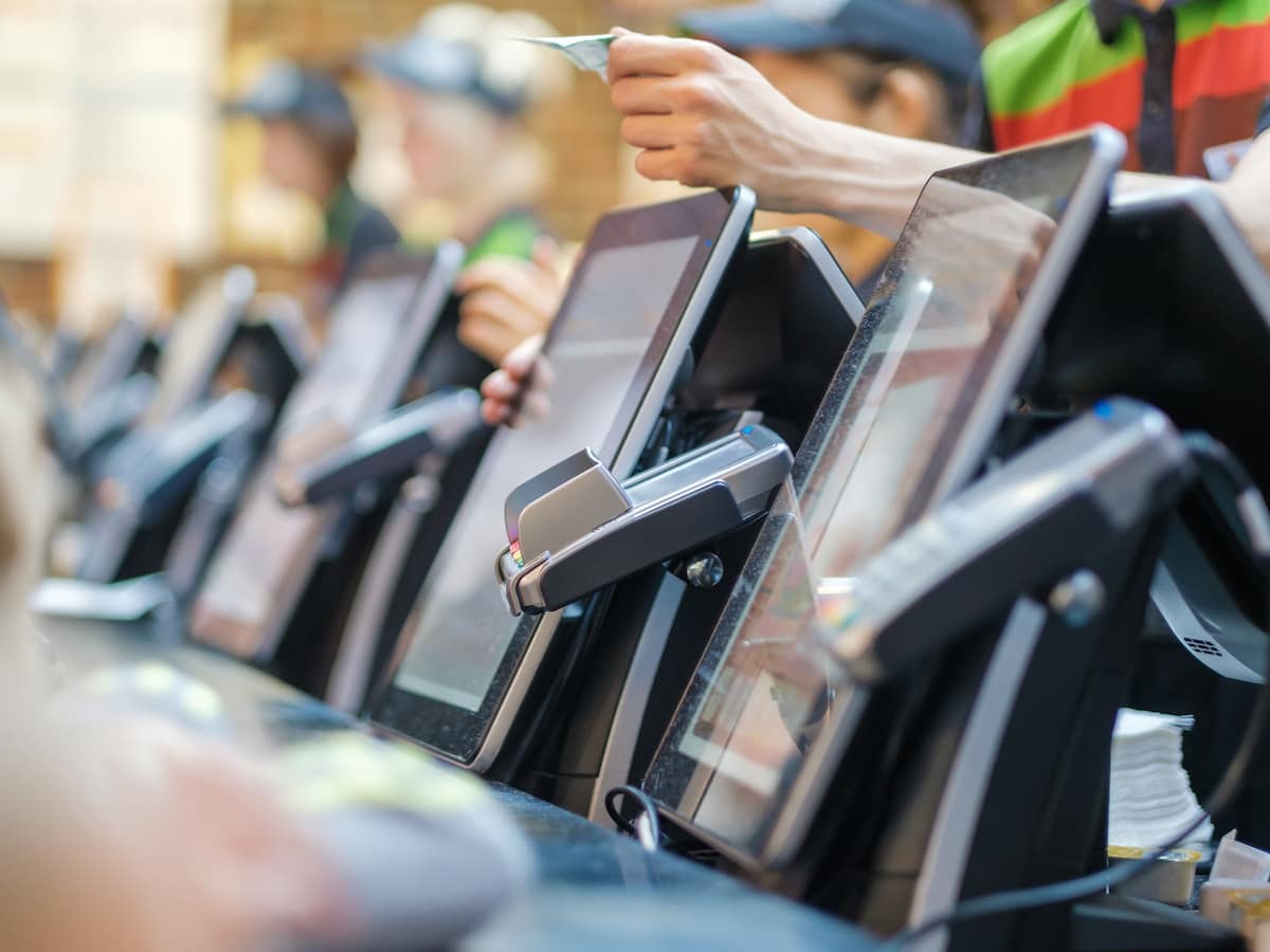 Row of order desks with computer screen and card payment terinal in fast food restaurant