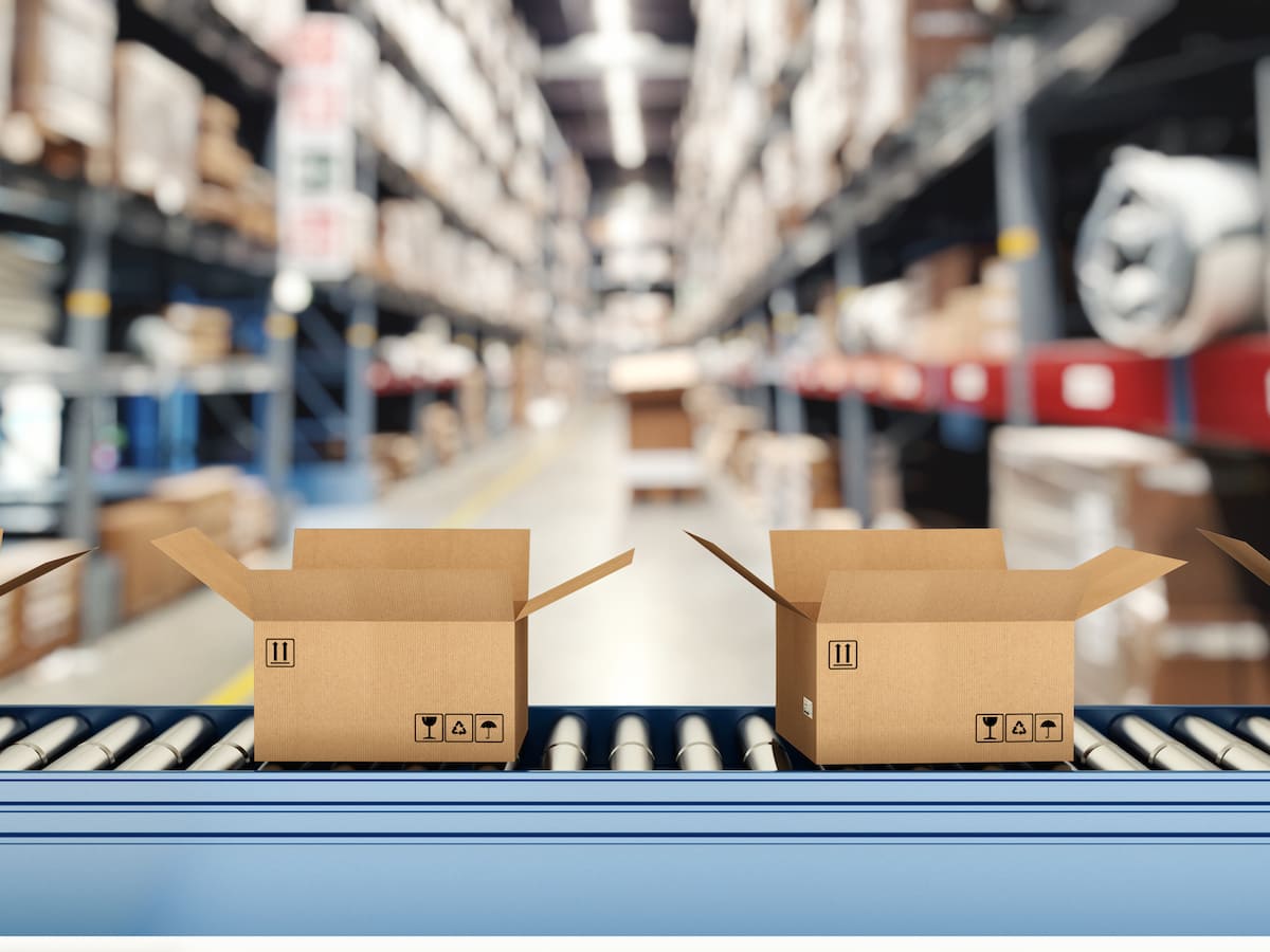 Cardboard boxes on conveyor roller with racks on background